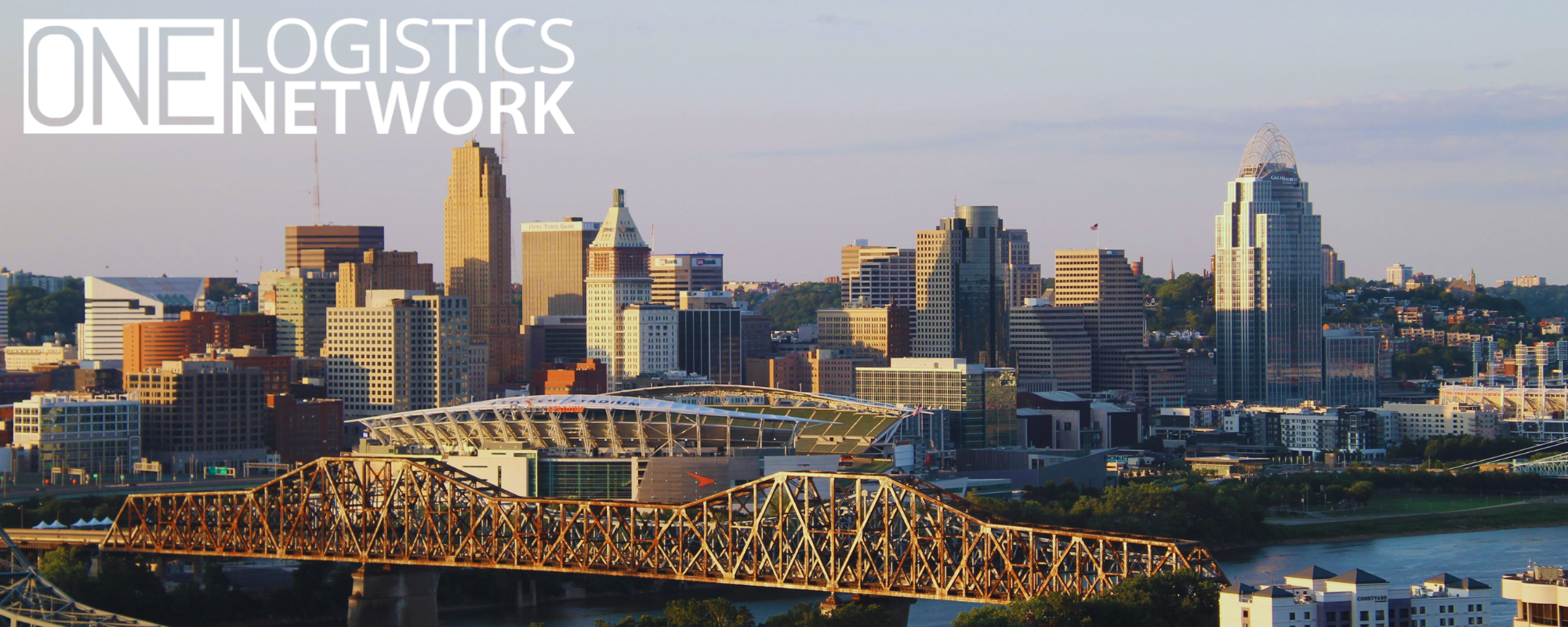 Downtown Cincinnati skyline at dusk, with the One Logistics Network office building illuminated among other high-rises.