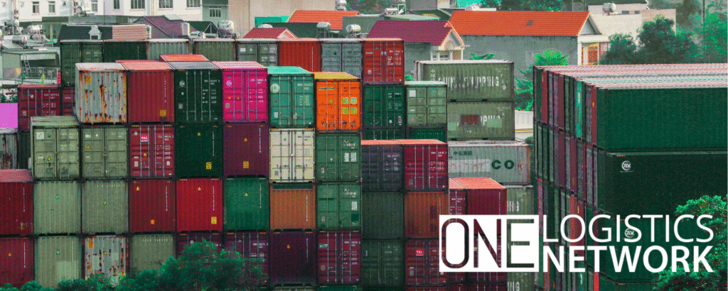 Stacks of colorful shipping containers at a busy port symbolizing the end of the freight frenzy and a shift to logistics uncertainty.