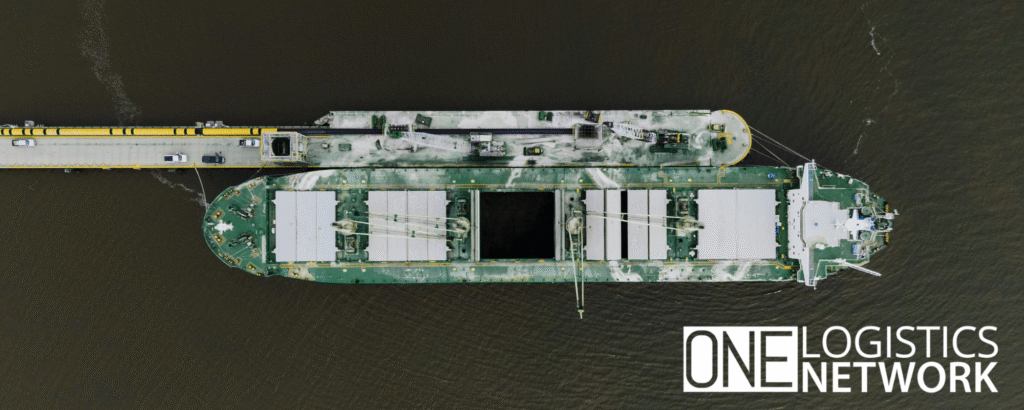 Barge loaded with shipping containers navigating congested waters, symbolizing the impact of tariffs on global trade and supply chains.